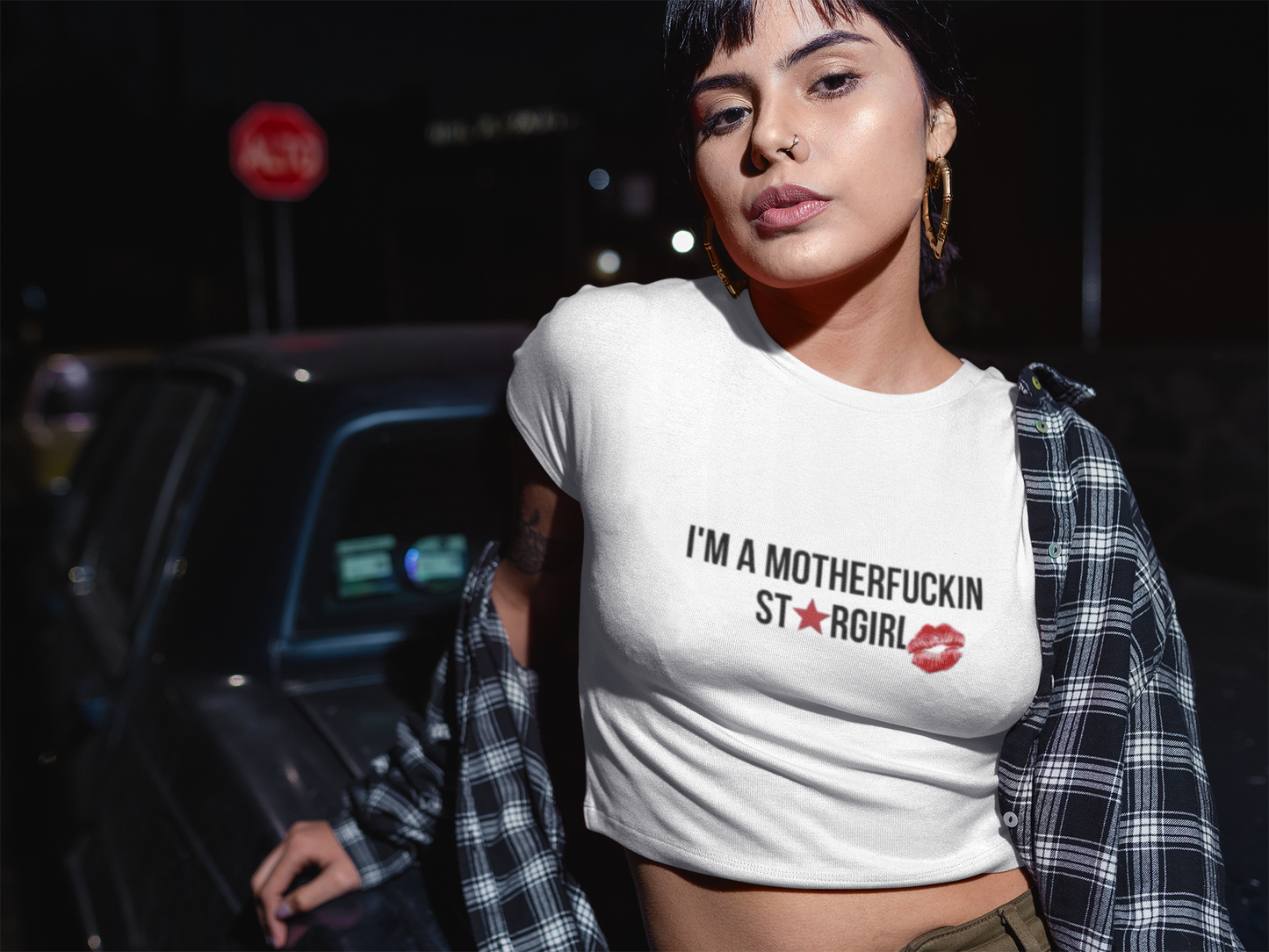 Edgy Hispanic woman modeling a Star Girl crop top with plaid shirt in nighttime city vibe