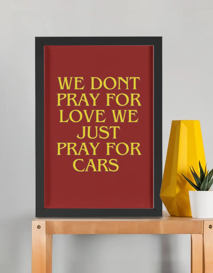 We Pray For Cars framed poster — bold yellow serif typography on red background in premium black frame, car lover wall art