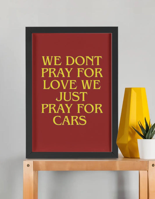 We Pray For Cars framed poster — bold yellow serif typography on red background in premium black frame, car lover wall art