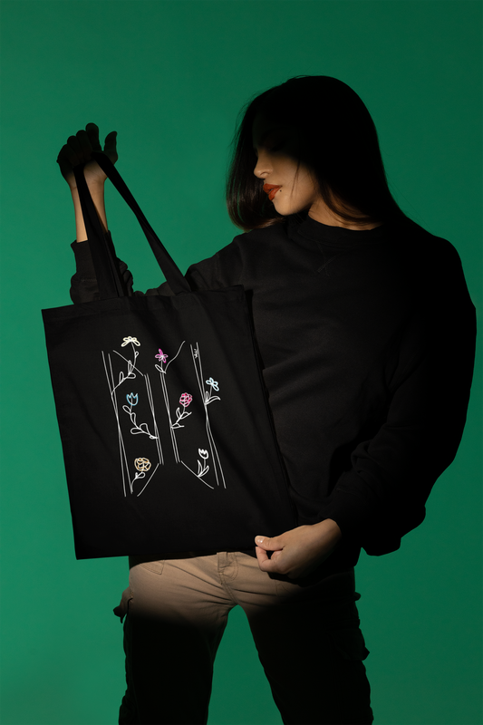 Woman showcasing BTS wildflower logo black tote bag in studio — K-pop ARMY fan art by amhype